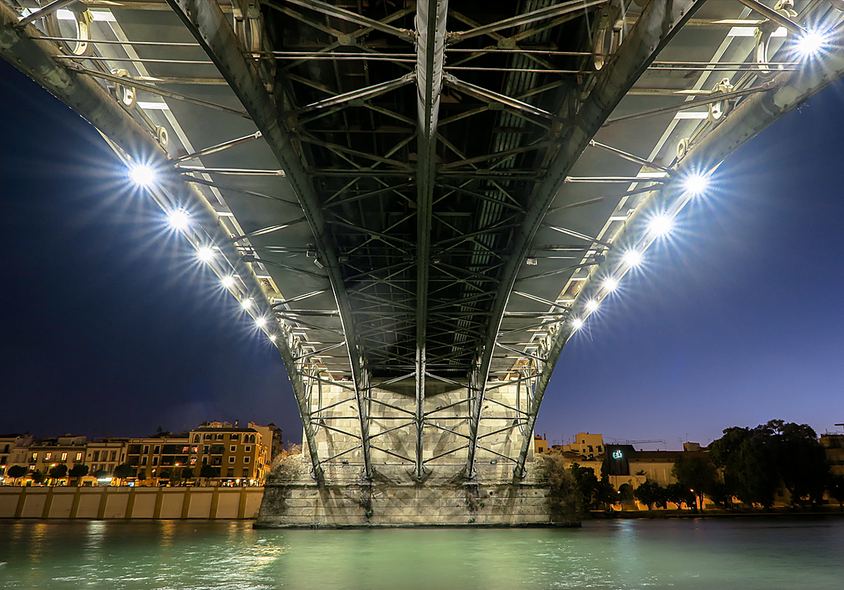 Vista de la parte inferior del Puente de Triana desde el Paseo Marqués de Contadero, con el viejo arrabal de fondo