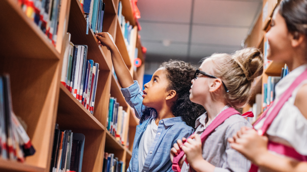 Grupo de niños cogiendo libros en la biblioteca