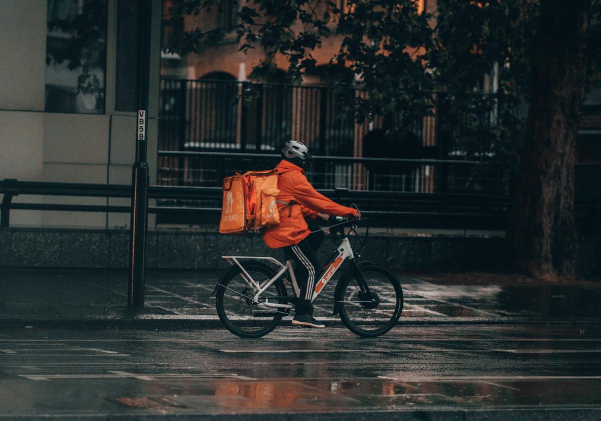 Repartidor en bici bajo la lluvia
