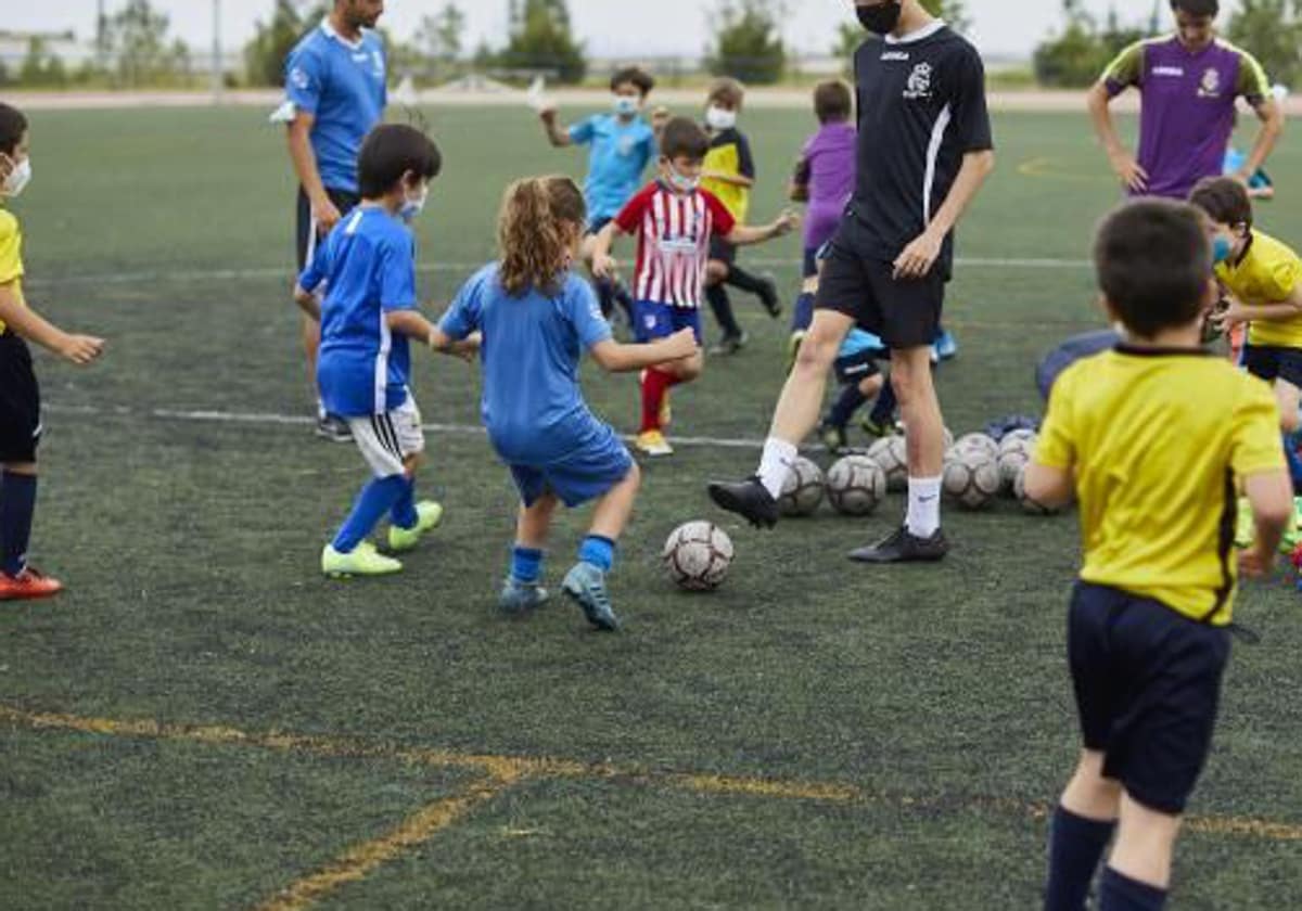 Una niña jugando a fútbol con otros niños, en una imagen de archivo