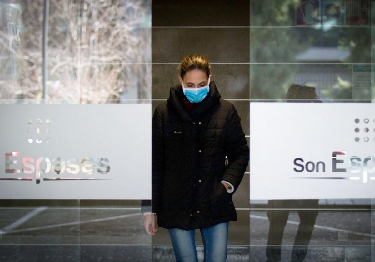 Una mujer con una mascarilla saliendo del hospital