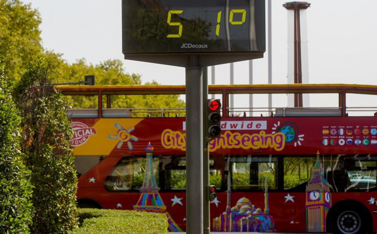 Un autobús turístico pasa por delante de un termómetro que marca 51 grados en Sevilla capital
