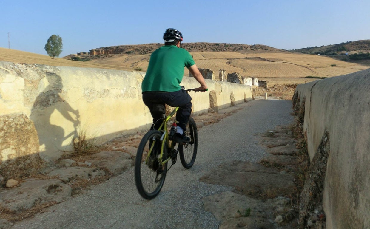 Un ciclista pasea por delante de unos restos arqueológicos