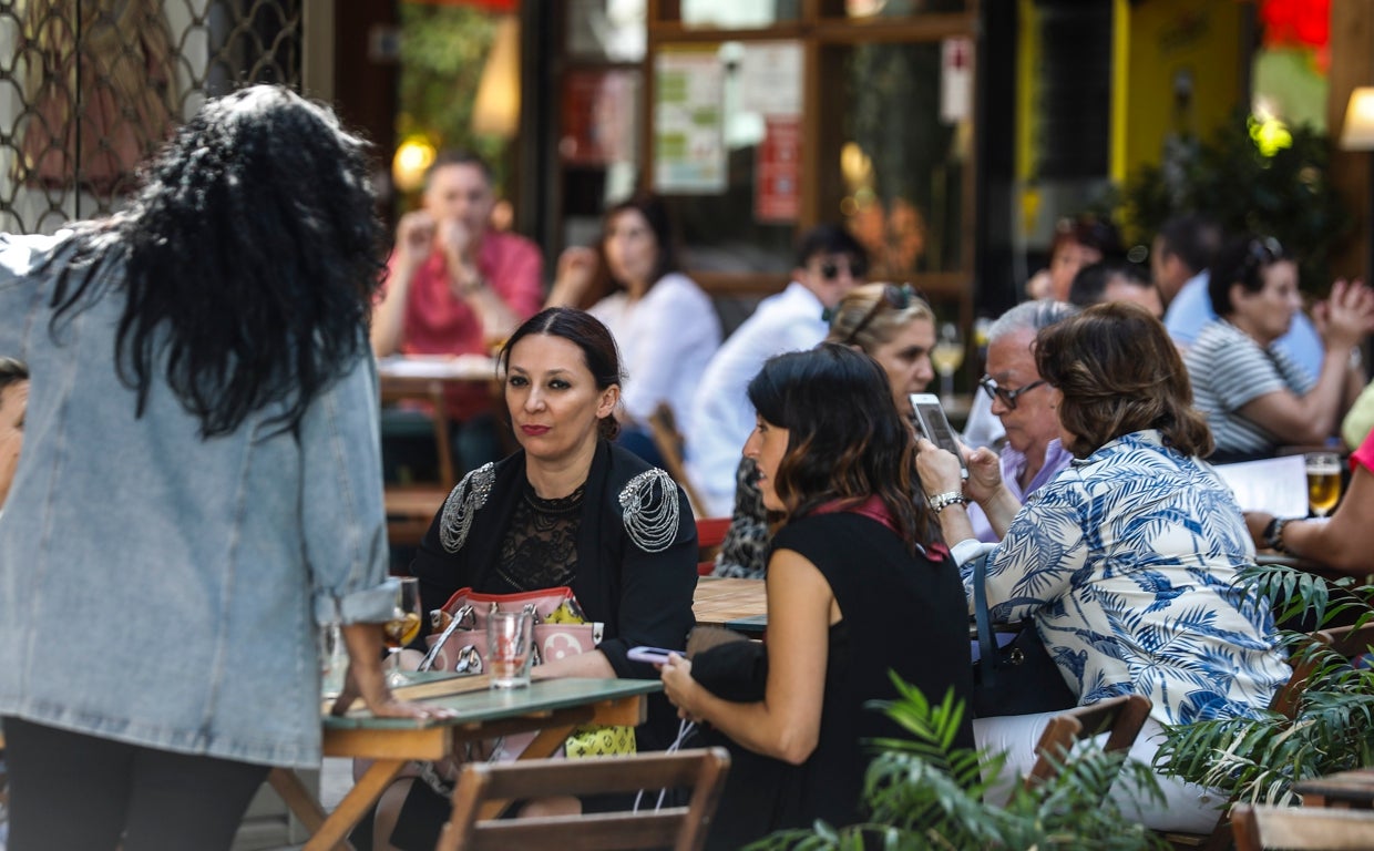 Varias personas conversan en la terraza de un bar de Sevilla