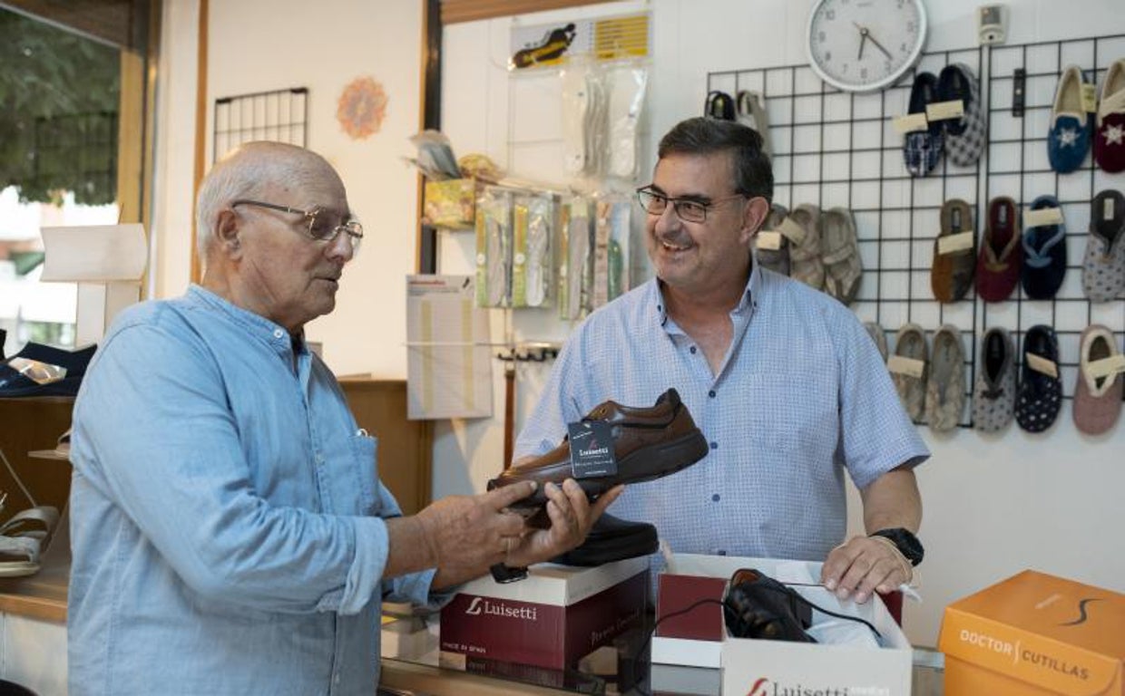 José Luis Romero, a la derecha, con un vecino en su zapatería