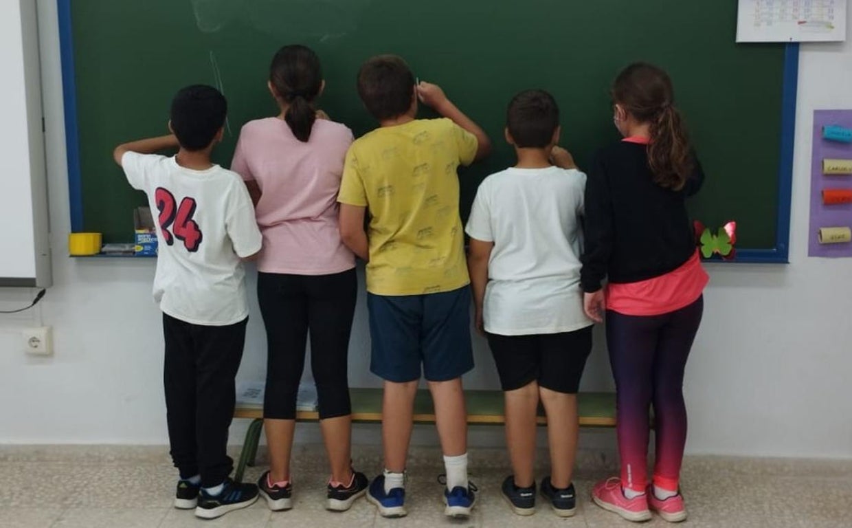 Varios alumnos de un colegio de Sevilla escriben en la pizarra