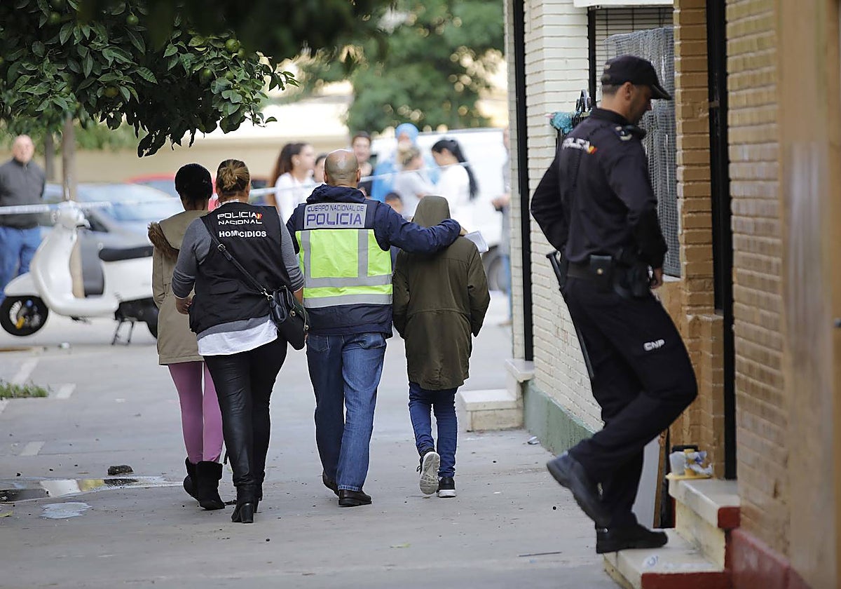 Un agente de la Policía Nacional acompaña al hijo de una mujer que mataron en Los Pajaritos en 2018