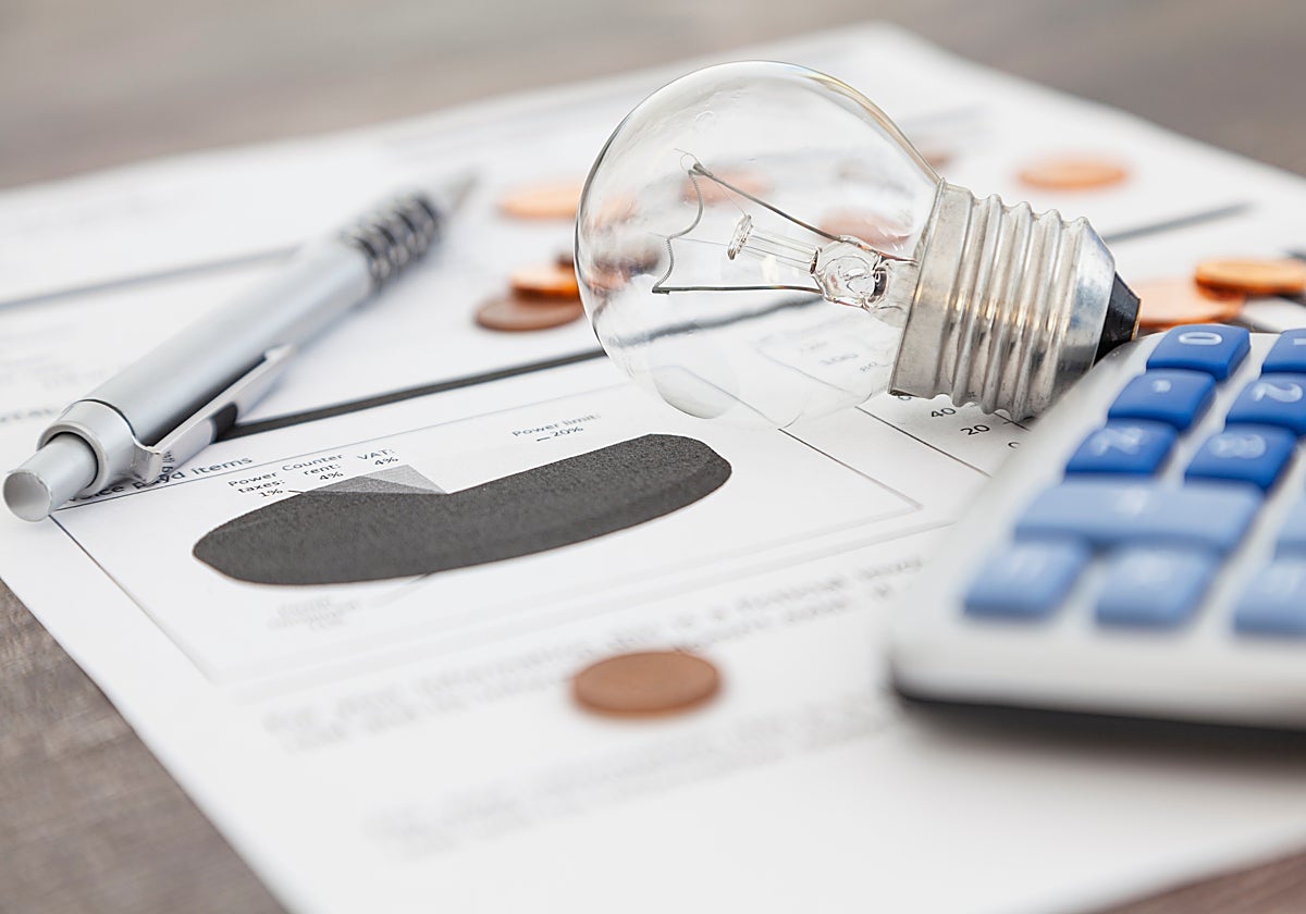 Fotografía de archivo de una factura junto a una bombilla y una calculadora