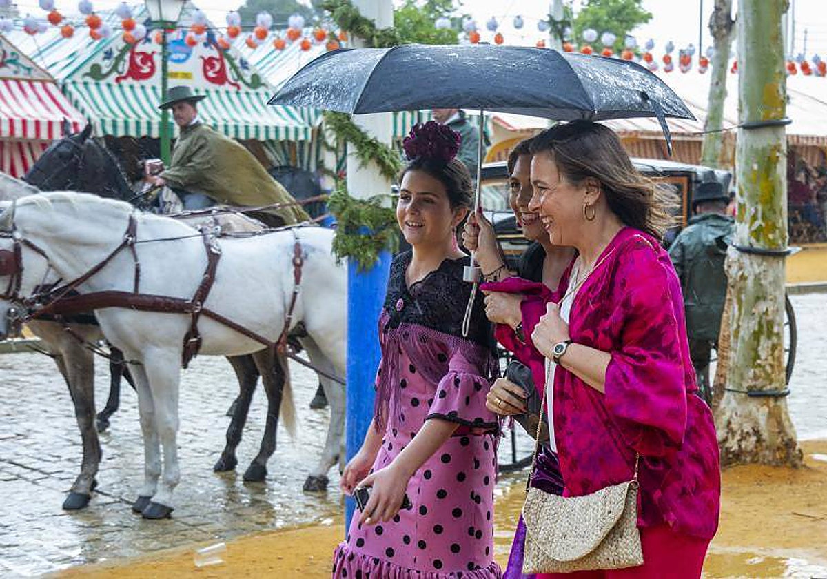 Tres mujeres se resguardan de la lluvia caída el 2 de mayo de 2022, la última vez que llovió en Feria