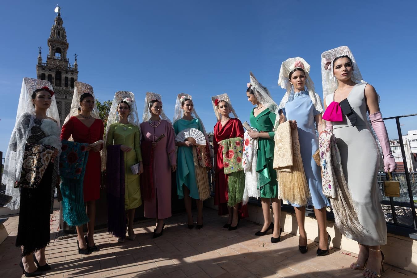 Unas jóvenes con mantilla blanca posan con la Giralda al fondo en la jornada de la Mantilla blanca