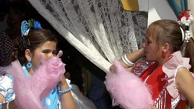 Dos niñas comen algodón dulce en la Feria