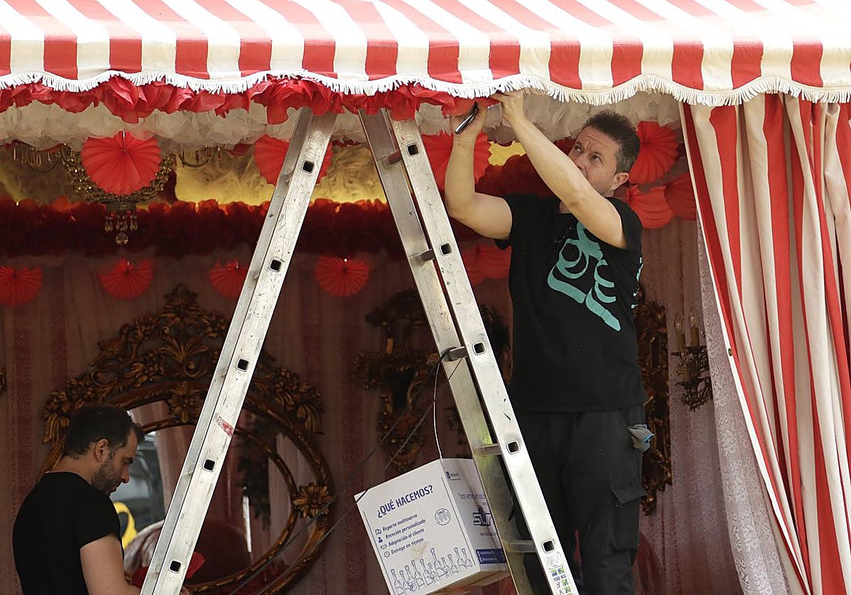 Un trabajador fija los farolillos en una caseta