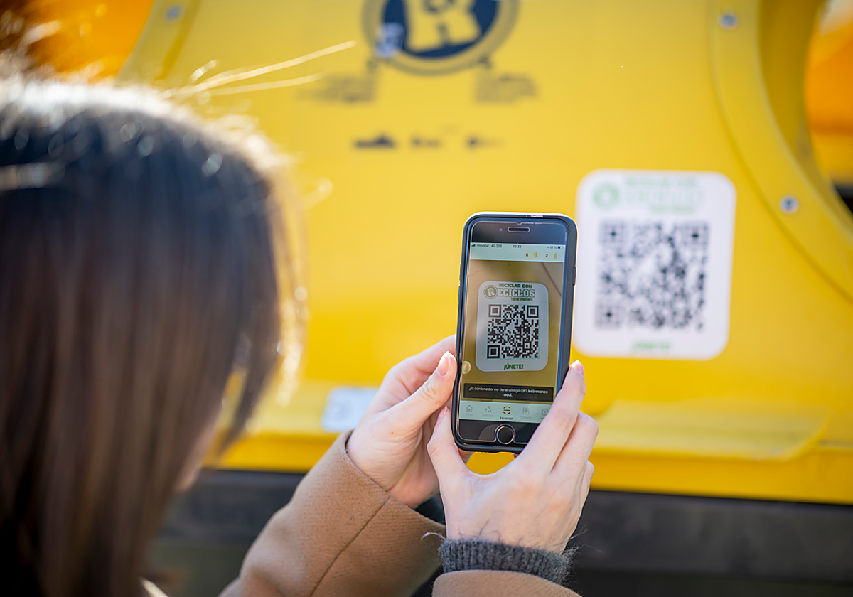 Una usuaria de RECICLOS escanea el código QR de un contenedor amarillo