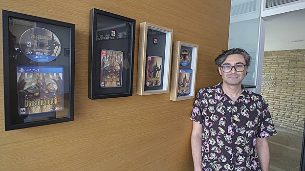 Mauricio García junto a las caratulas de Blashemous