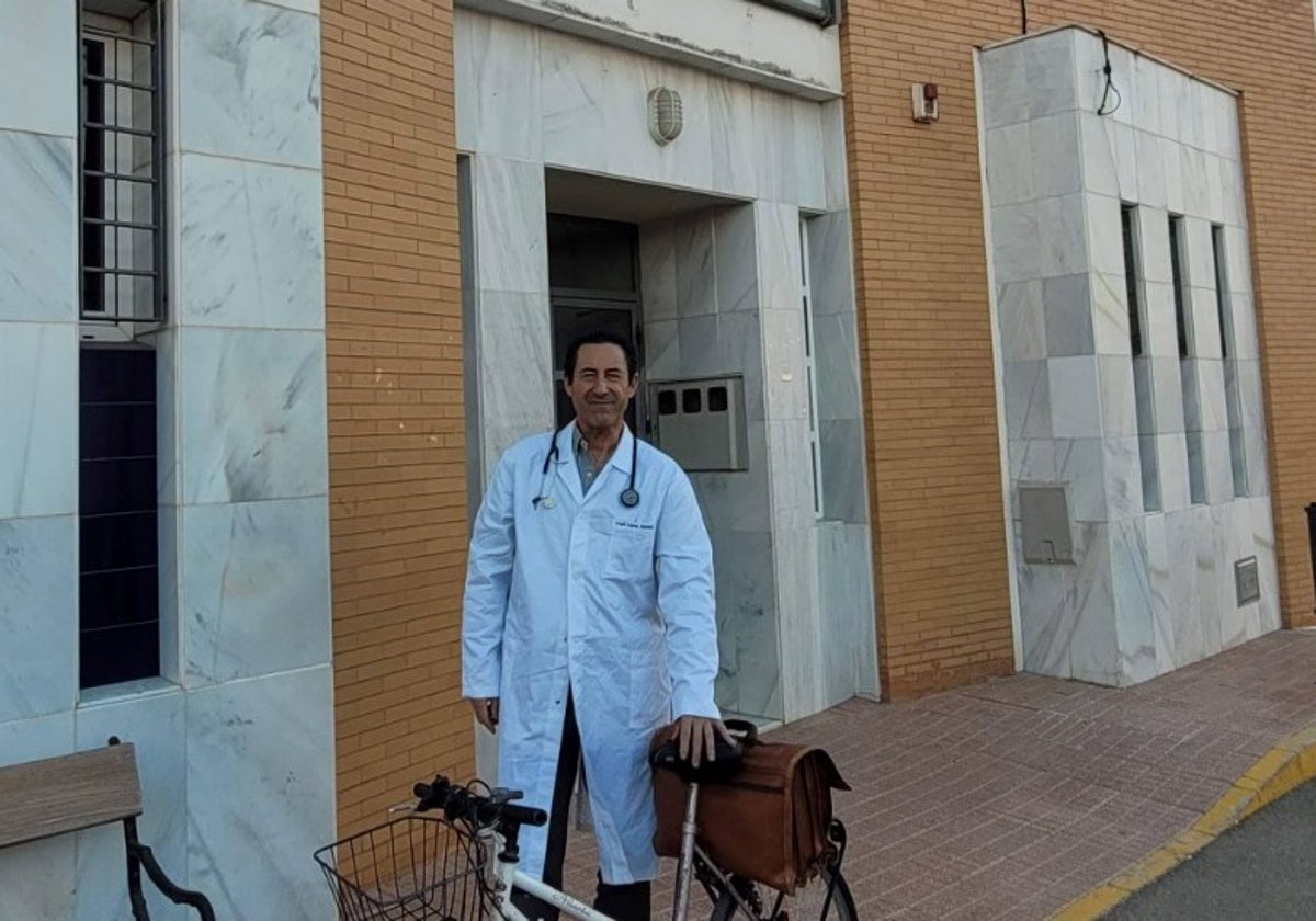 El médico Ángel López, en la puerta del ambulatorio de Cañada Rosal, junto a la bicicleta en la que se desplaza