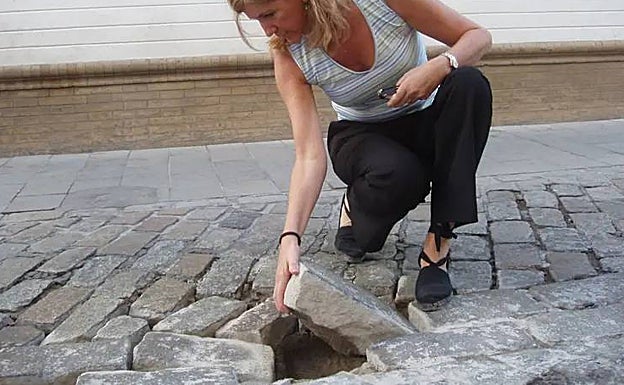 Una mujer comprueba el estado de los adoquines de la calle Monsalves