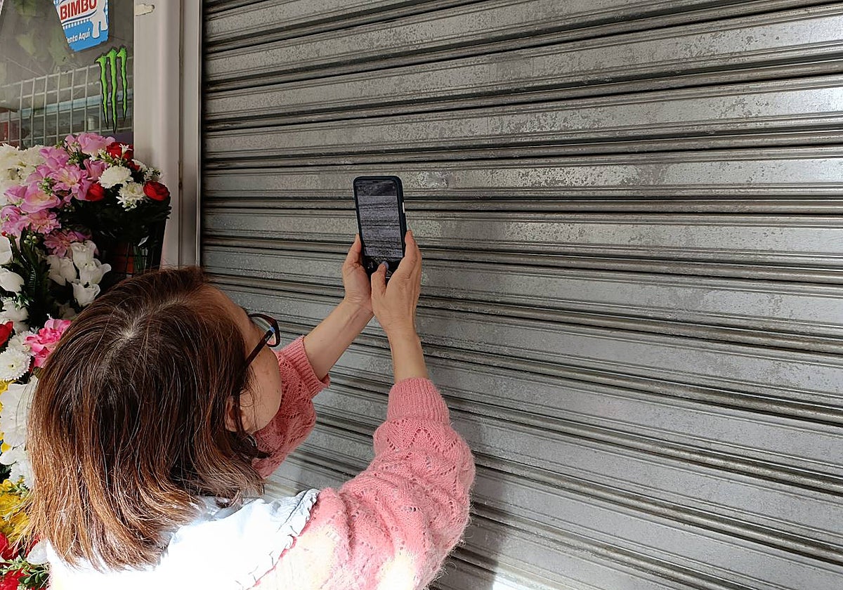 La propietaria de un bazar fotografía los impactos de las balas en su negocio