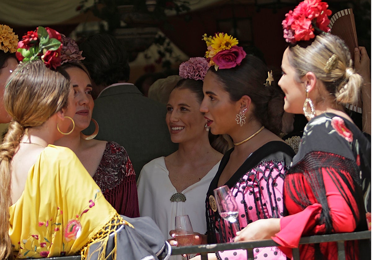Flamencas charlan en la entrada de una caseta durante la feria