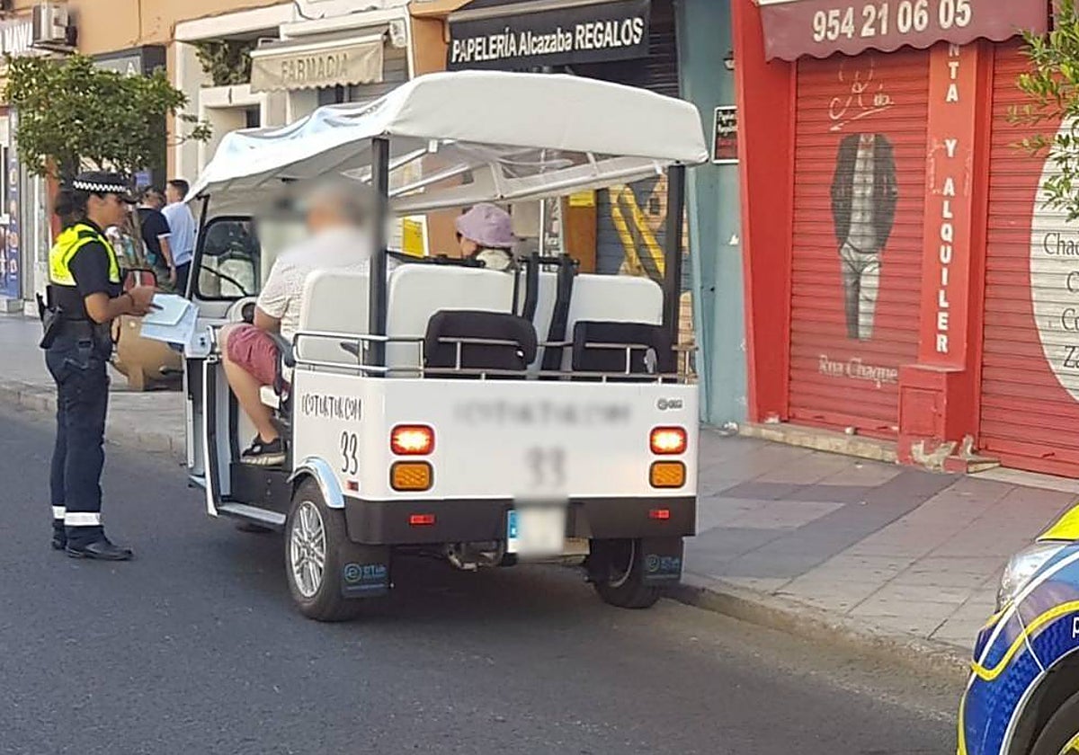 Una agente de la Policía Local impone una sanción al conductor de un tuk tuk en Sevilla