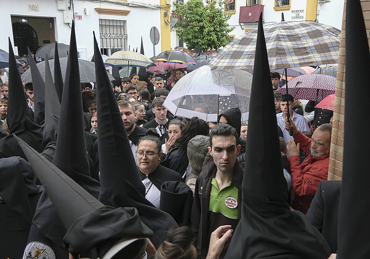 Nazarenos de la hermandad de Santa Genoveva, mientras llovía en el barrio del Tiro de Línea