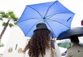 Dos nazarenos de las Siete Palabras, entre paraguas por la lluvia, este Miércoles Santo de la Semana Santa de Sevilla