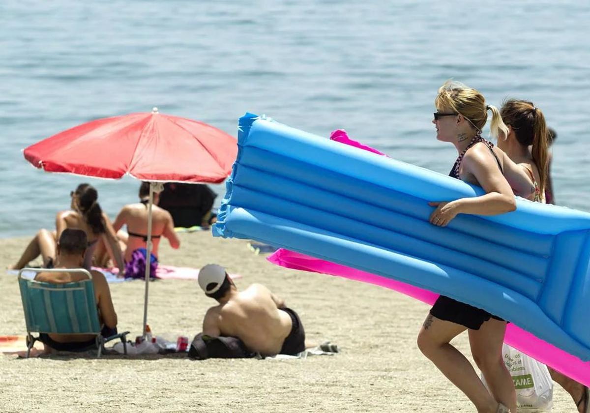 Varias personas, en una playa de Málaga, con una mujer en primer plano que se protege del sol con unas gafas