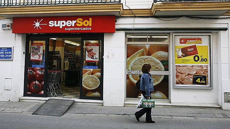 Una mujer camina junto a un supermercado de Supersol