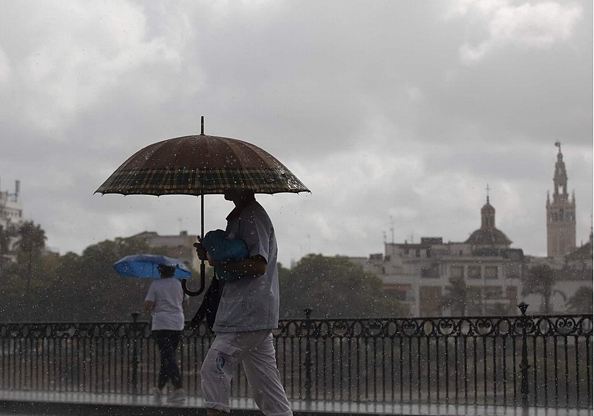 Gente caminando por el Puente de Triana con el paraguas durante un día de lluvia en Sevilla