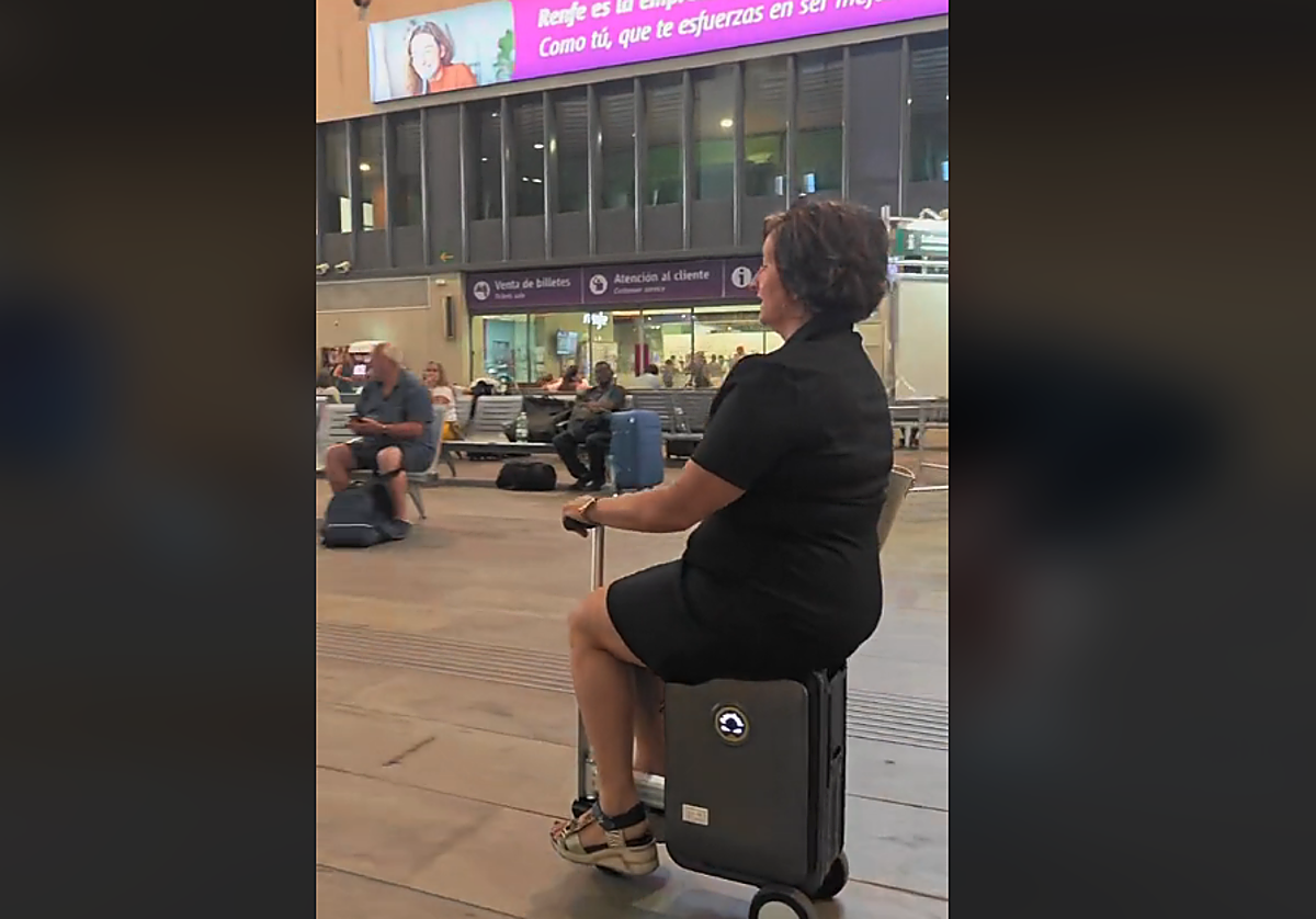 Una señora usando su maleta inteligente en la estación de Santa Justa