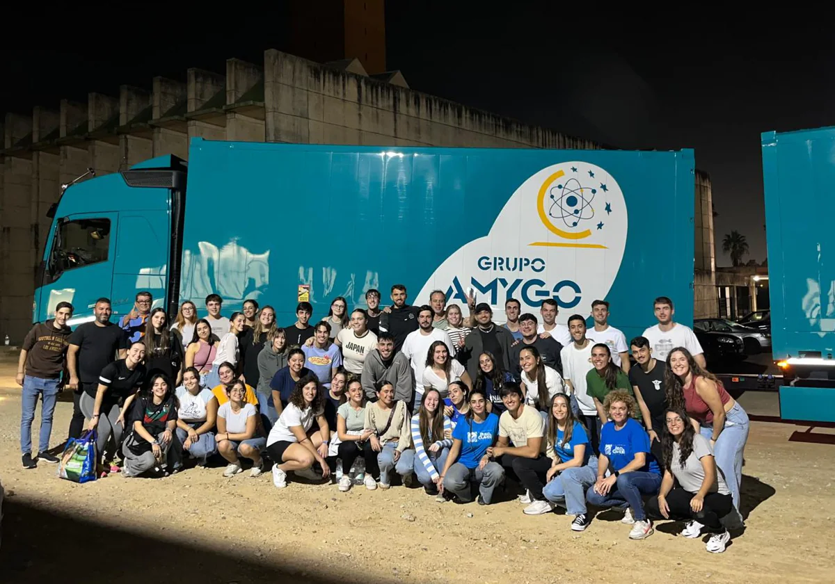 Alumnos de la Universidad Pablo de Olavide junto al tráiler que ha transportado las 23 toneladas de productos a Valencia