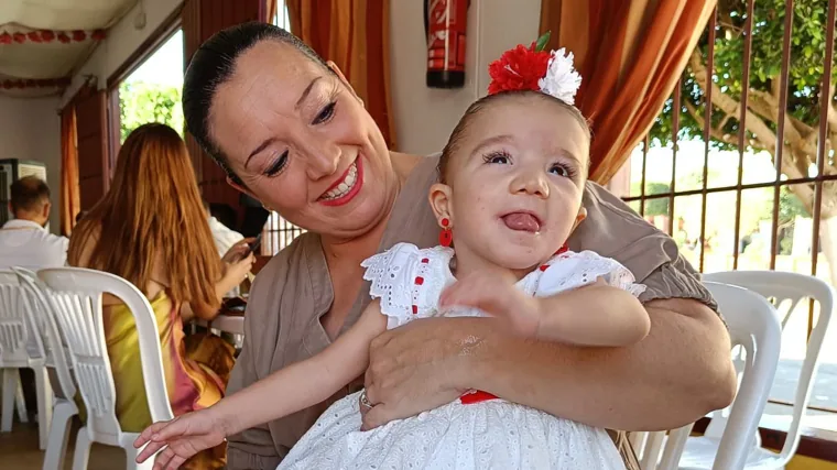 Elena con su madre en una caseta de feria. Un cartel en su carro avisa de que la gente no se acerque a ella, ni la toque ni la bese