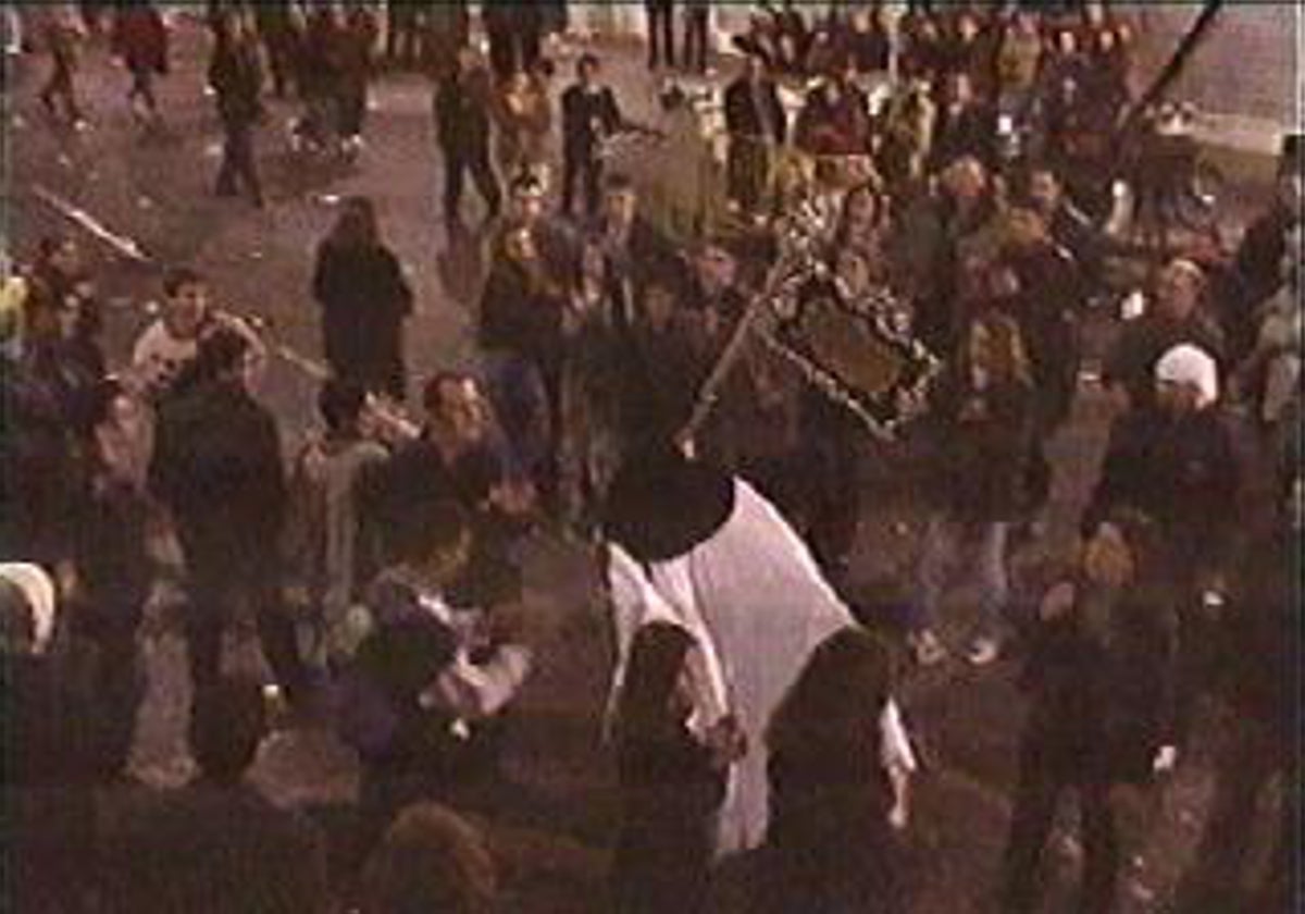 Un nazareno de la hermandad de los Gitanos sale huyendo tras los primeros incidentes de la Madrugada del 2000