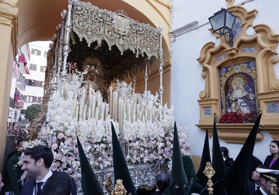 El paso de palio de la Esperanza de Triana cruza bajo el arco del Postigo en la Madrugada