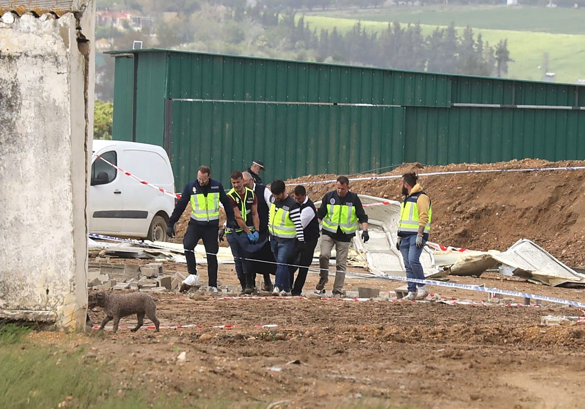 Agentes de la Policía Nacional y empleados del tanatorio Nervión trasladan el cuerpo de una de las víctimas en Coria del Río