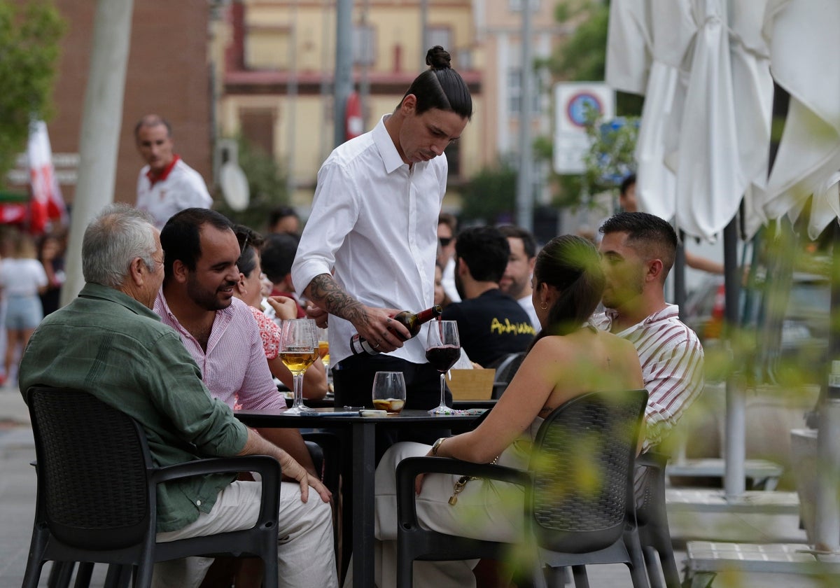 Un trabajador de la hostelería atiende una terraza en el Centro de Sevilla
