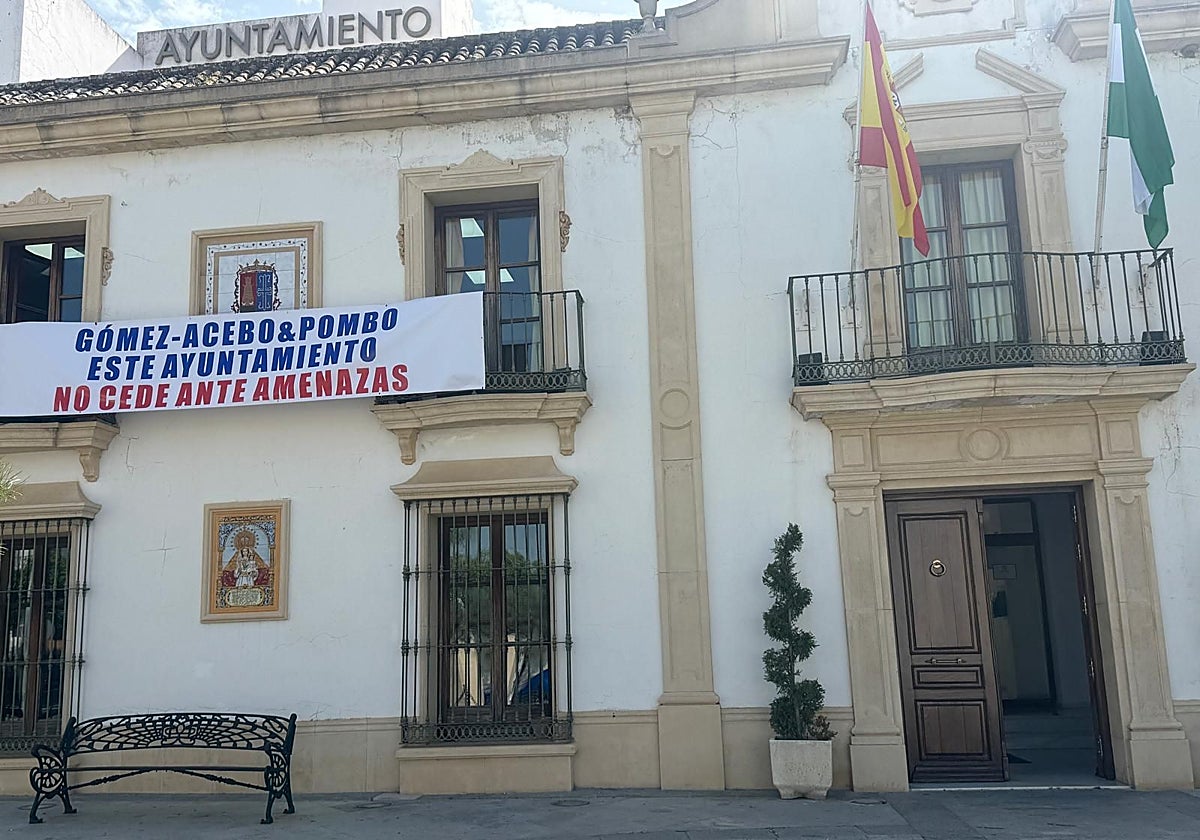 Fachada el Ayuntamiento de Burguillos con una pancarta denunciando las amenazas del despacho de abogados del fondo buitre