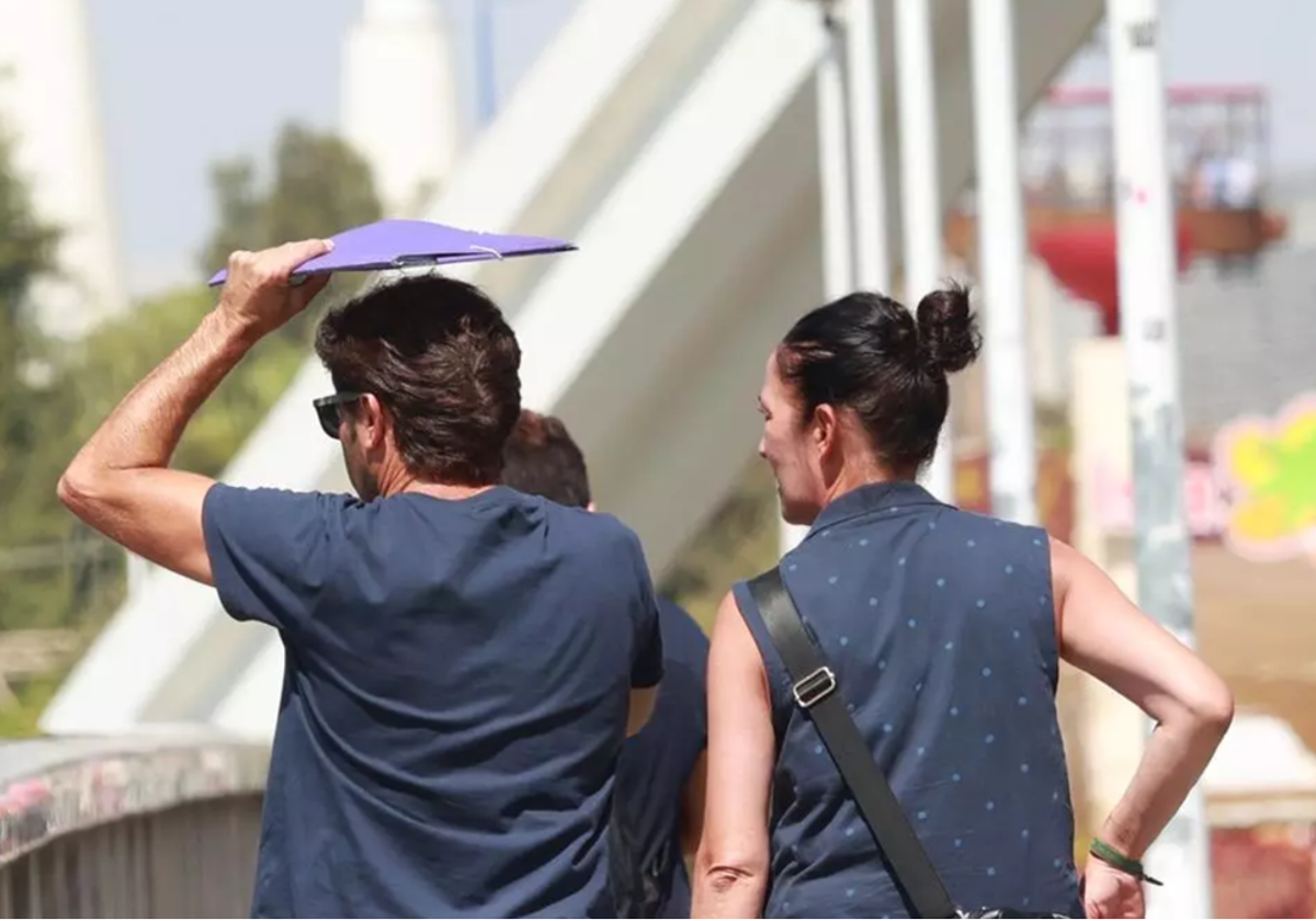 Personas cruzando el Puente de la Barqueta en un día con mucho sol en Sevilla