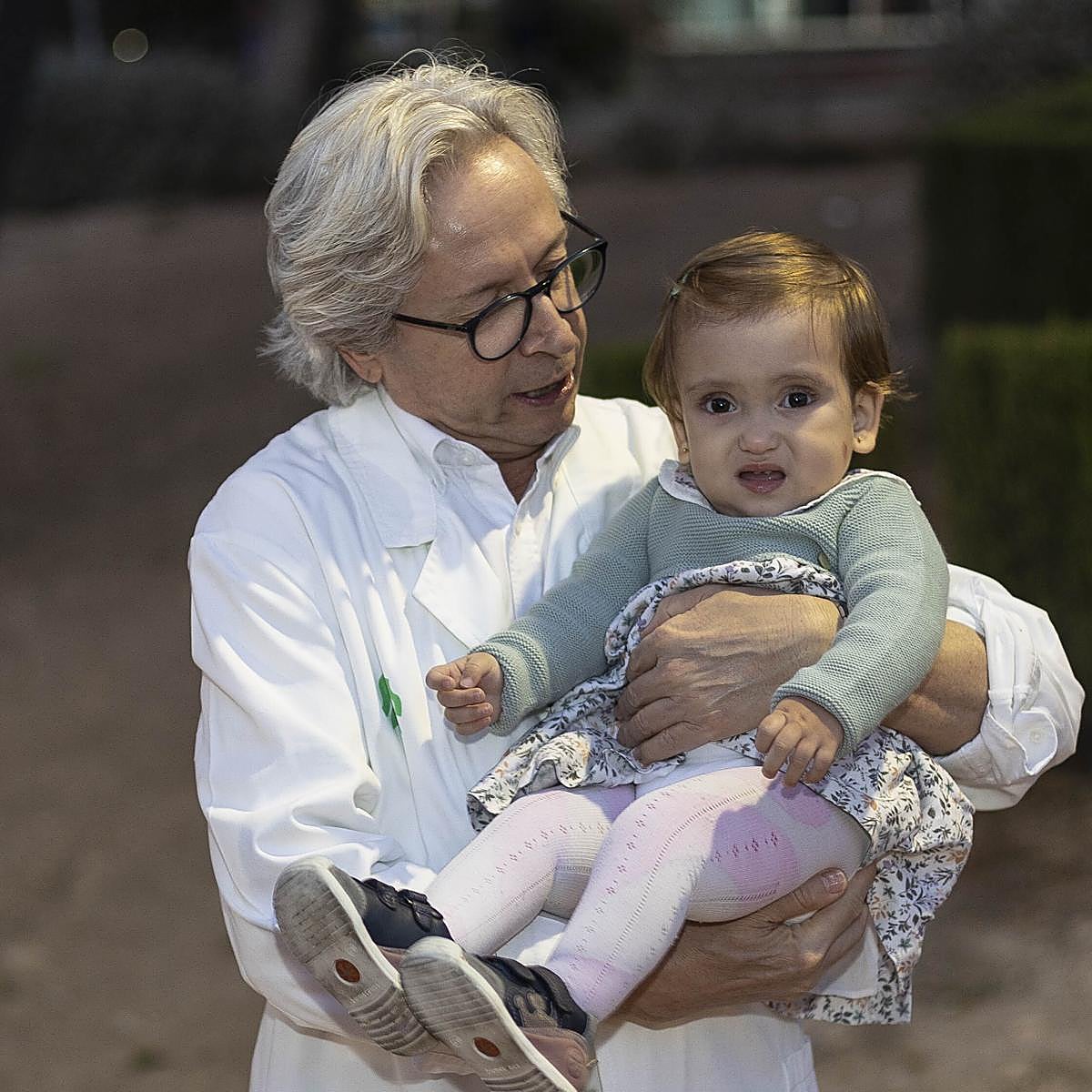 Guillermo Antiñolo toma en brazos a Elena Rambla Listán, a la que operó con éxito de espina bífida en el Virgen del Rocío en 2022. La imagen es de diciembre de 2023
