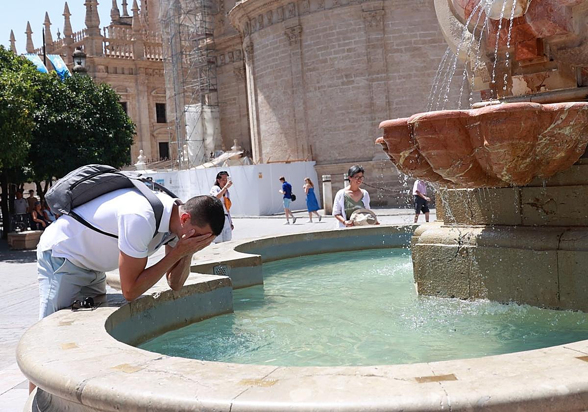 Un joven se refresca en una fuente