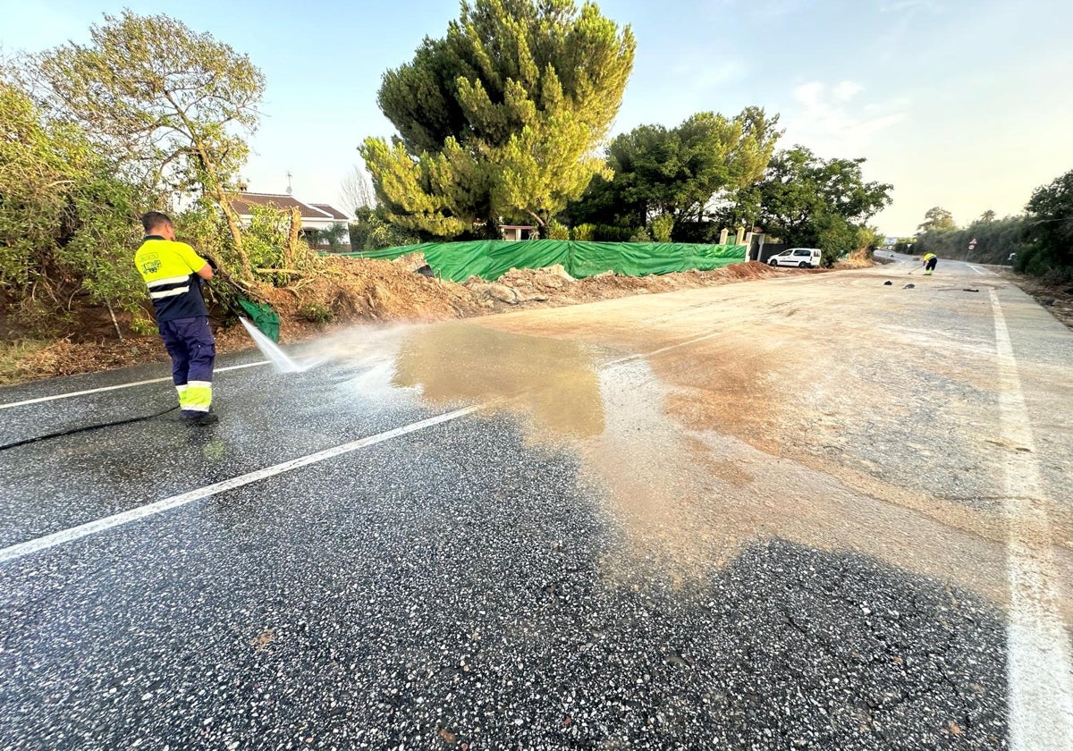 Trabajadores limpiando la carretera después de estallar la tubería y arrastrar barro hacia las viviendas