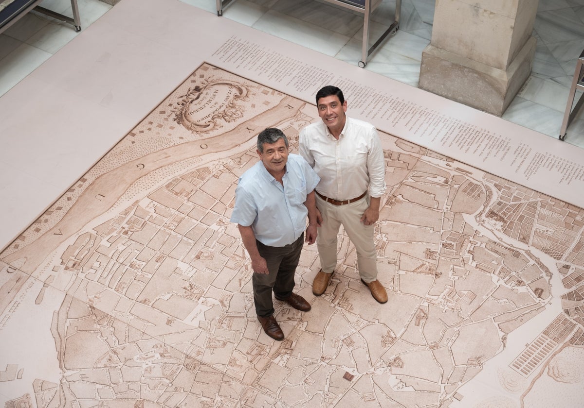 Marcos Fernández y Braulio Vázquez, directores del Archivo Municipal y del Archivo Histórico Provincial, sobre la copia del plano de Sevilla de Olavide, que se muestra en la exposición
