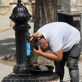 Un hombre se refresca en una fuente de Sevilla este martes
