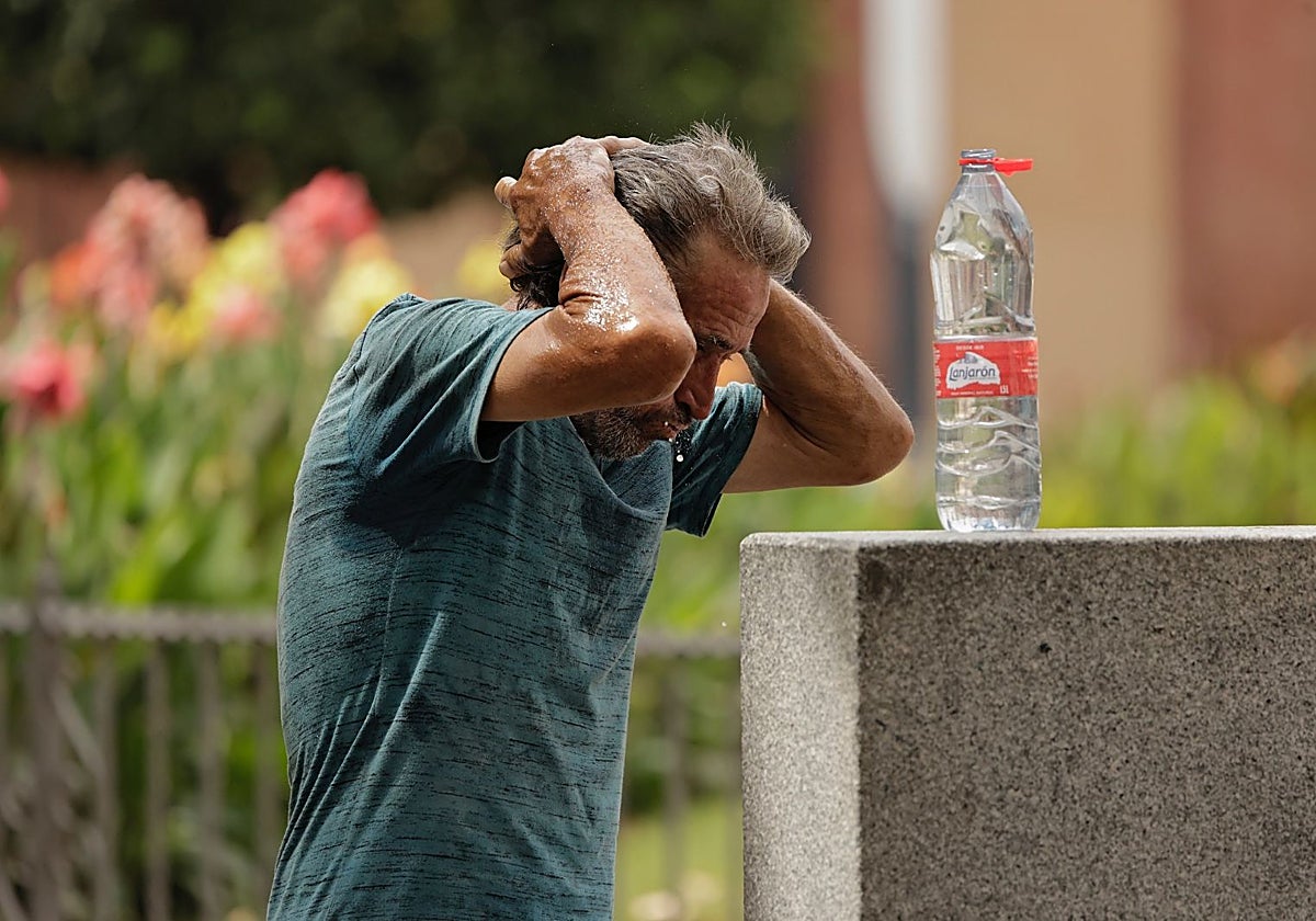 Un hombre se refresca en Sevilla en plena ola de calor