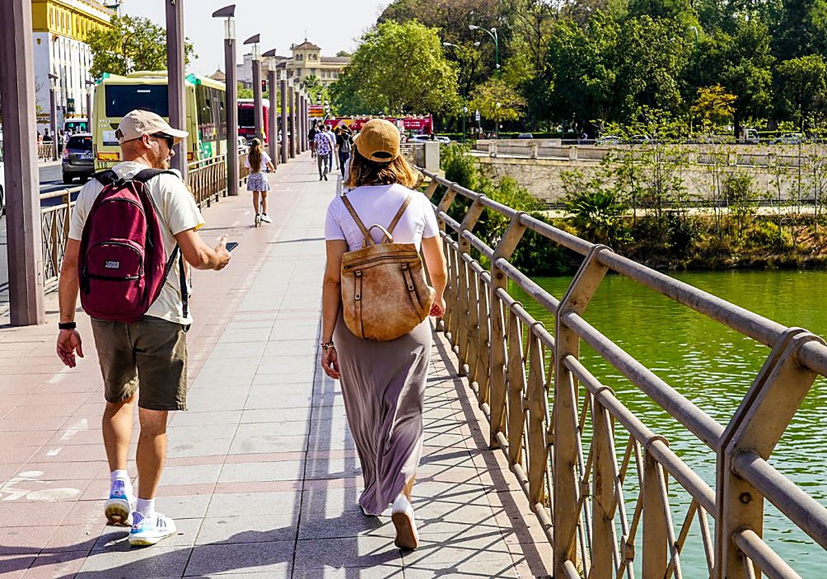 Dos personas pasean por el Puente de San Telmo, en Sevilla