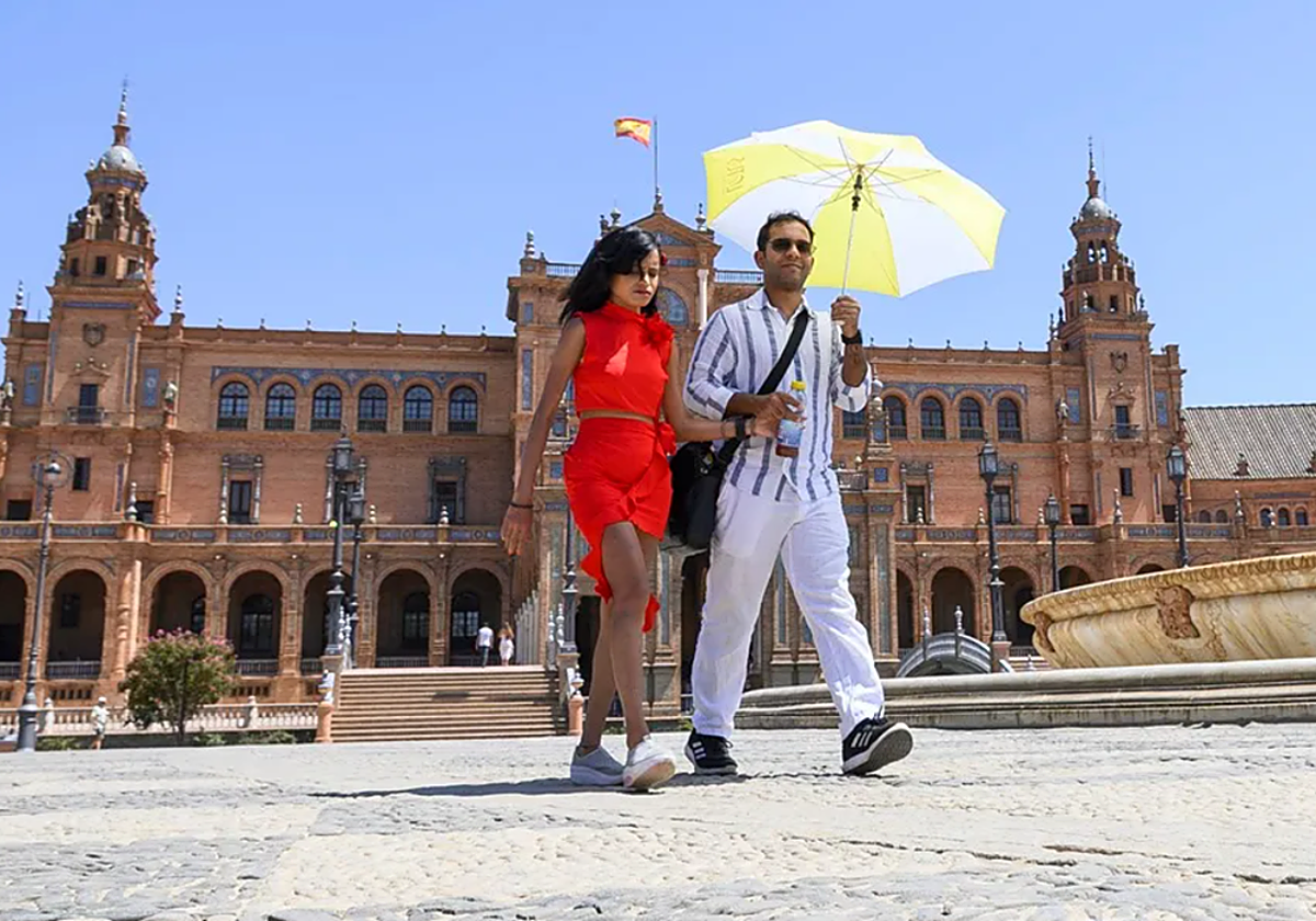 Una pareja pasea por la Plaza de España durante una jornada de calor en otoño