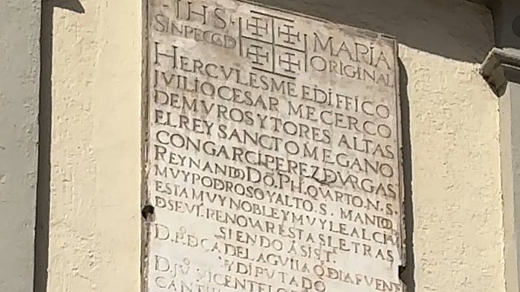 La placa renacentista de la desaparecida Puerta de Jerez, recolocada en el chaflán de un edificio de la actual plaza en el siglo XIX. Grabada en el siglo XVI, recuerda el célebre lema: «Hércules me edificó, Julio César me cercó de muros y torres altas, y el Rey Santo me ganó con Garci Pérez de Vargas…» citando en cinco versos lo más granado de la historia de Sevilla