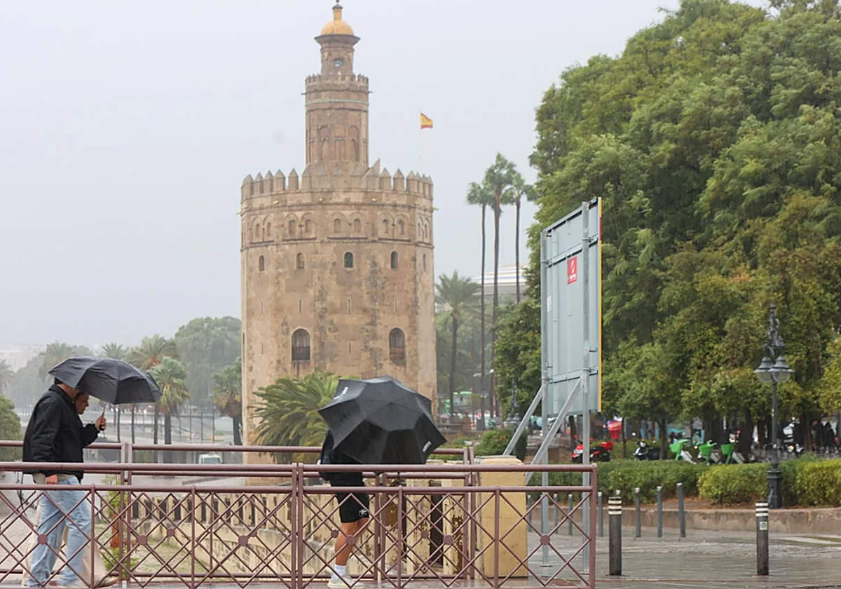 Gente cruzando el Puente de San Telmo durante un día de lluvia en Sevilla