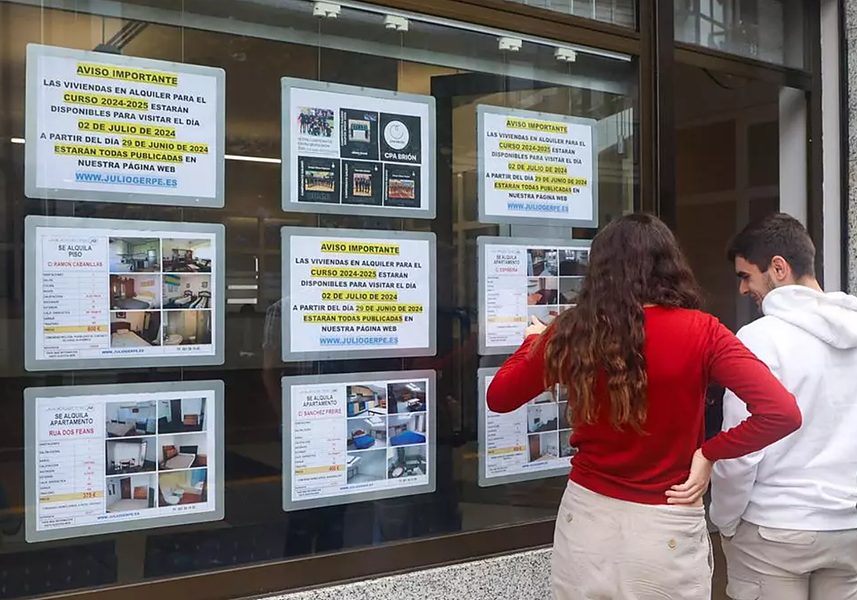 Un grupo de jóvenes mira anuncios de viviendas en alquiler en el escaparate de una inmobiliaria