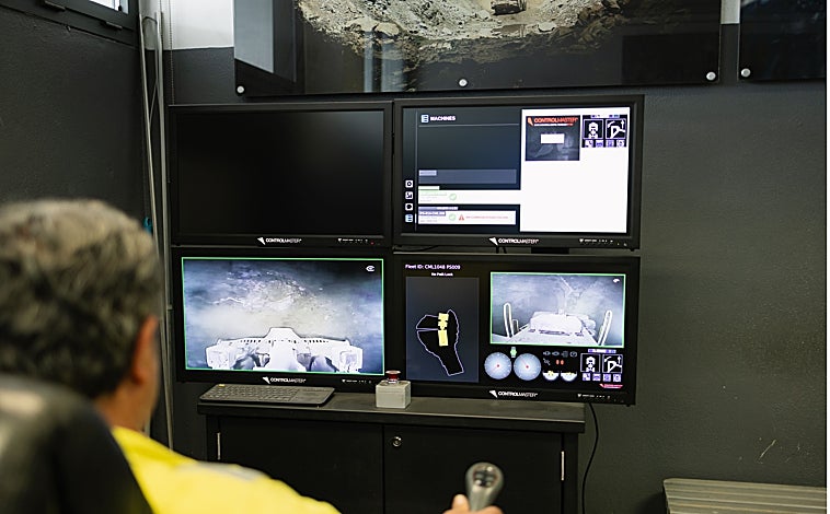 Imagen principal - Arriba, un trabajador maneja las máquinas que se encuentran a cientos de kilómetros bajo tierra. Abajo a la izquierda, vista de las instalaciones de Sandfire Matsa y a la derecha, detalle del mando con el que se mueve la maquinaria pesada.