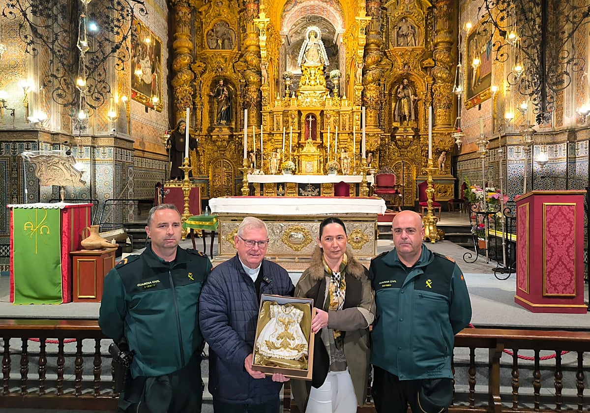 El rector del santuario de Consolación y la hermana mayor de la hermandad de Consolación reciben de la Guardia Civil el traje del Niño Jesús de la patrona de Utrera